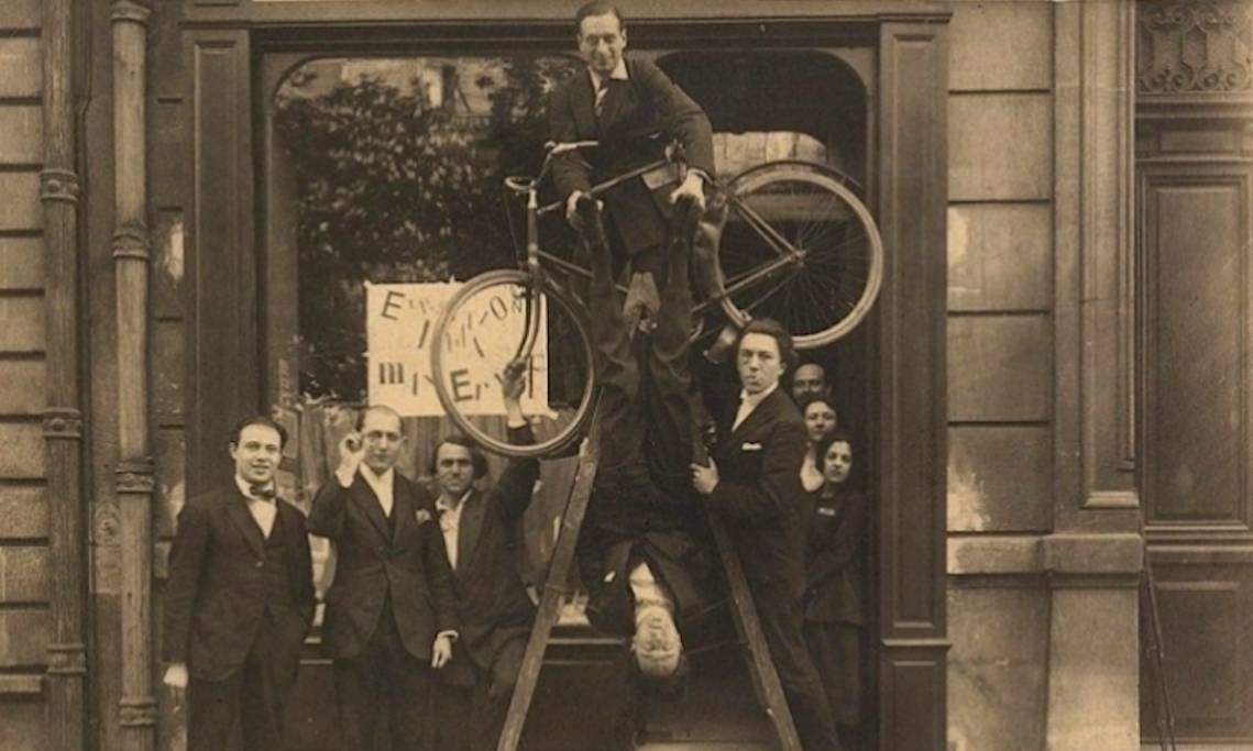 Devant l'entrée de l'exposition Max Ernst à Paris, Jacques Rigault la tête à l'envers avec, entre autres, André Breton et Philippe Soupault, 1921 - source : WikiCommons 