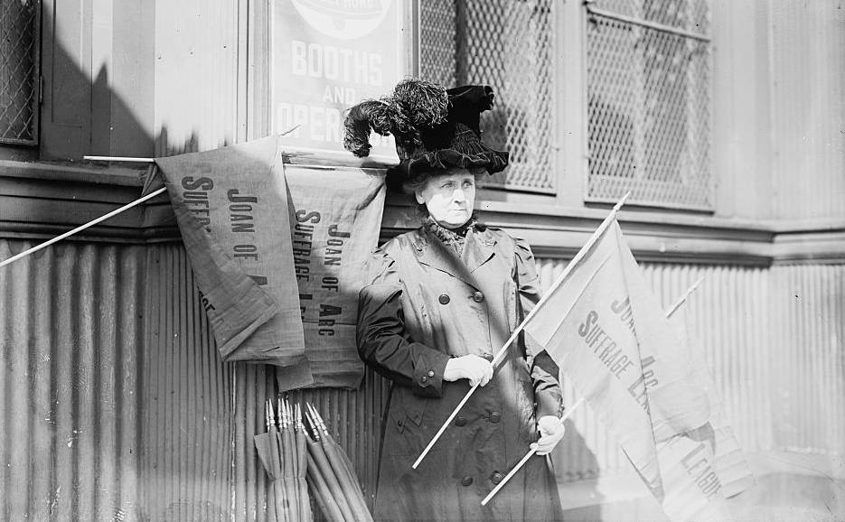 La suffragette Nellie van Slingerland tenant le drapeau de la Joan of Arc Suffrage League - source : Library of Congress